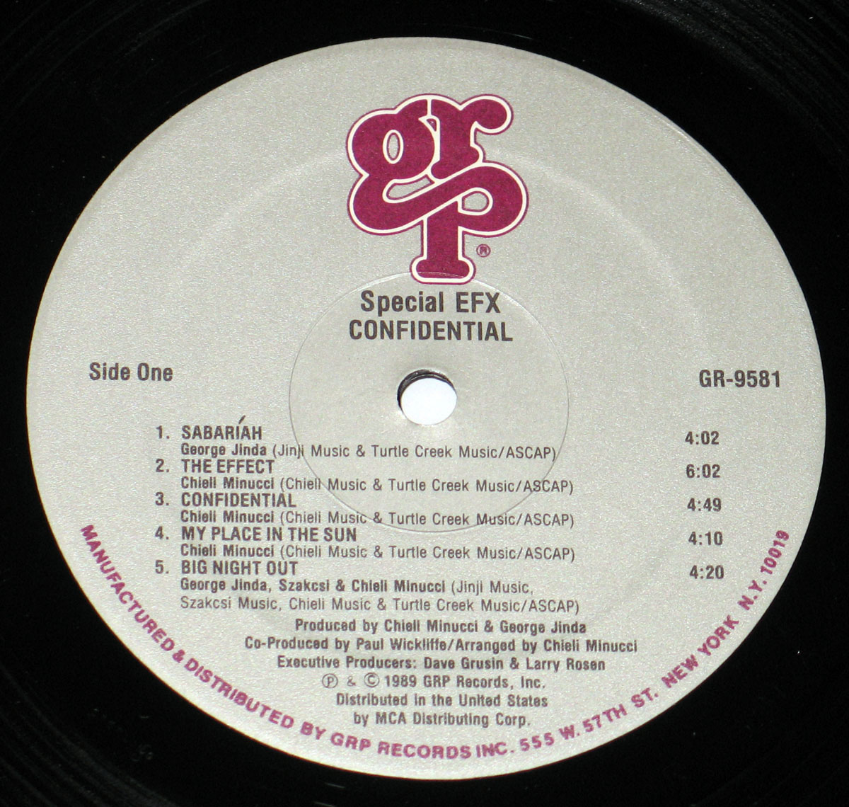 Vinyl record label of Special EFX's 1989 album Confidential, Side One, released on GRP Records. The label is a light grey background with bold magenta GRP logo at the top. Centered text reads Special EFX Confidential with the catalog number GR-9581 to the right. Song titles and timings are printed in black: Sabariah (4:02), The Effect (6:02), Confidential (4:49), My Place in the Sun (4:10), Big Night Out (4:20). Songwriting credits are listed for George Jinda, Chieli Minucci, and Szakcsi. Production credits name Chieli Minucci, George Jinda, Paul Wickliffe, Dave Grusin, and Larry Rosen. Around the edge, manufacturing and distribution information identifies GRP Records, 555 W. 57th St. New York, N.Y. 10019, distributed in the USA by MCA Distributing Corp.